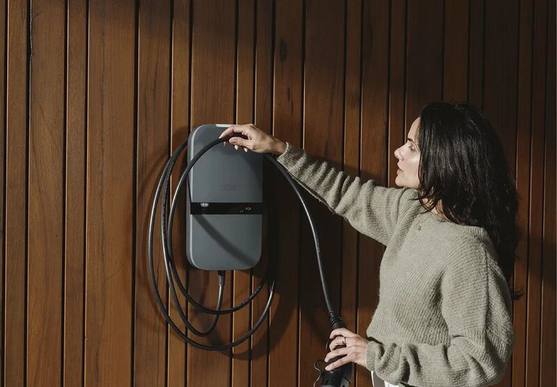 Vrouw hangt de laadkabel om haar wallbox.