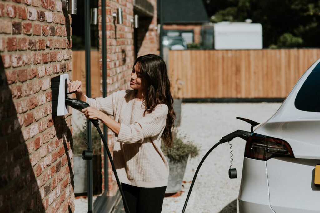 Vrouw laadt haar elektrische auto op met een laadpaal thuis.