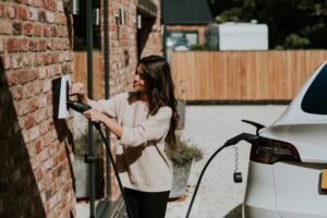Vrouw laadt haar elektrische auto op met een laadpaal thuis.